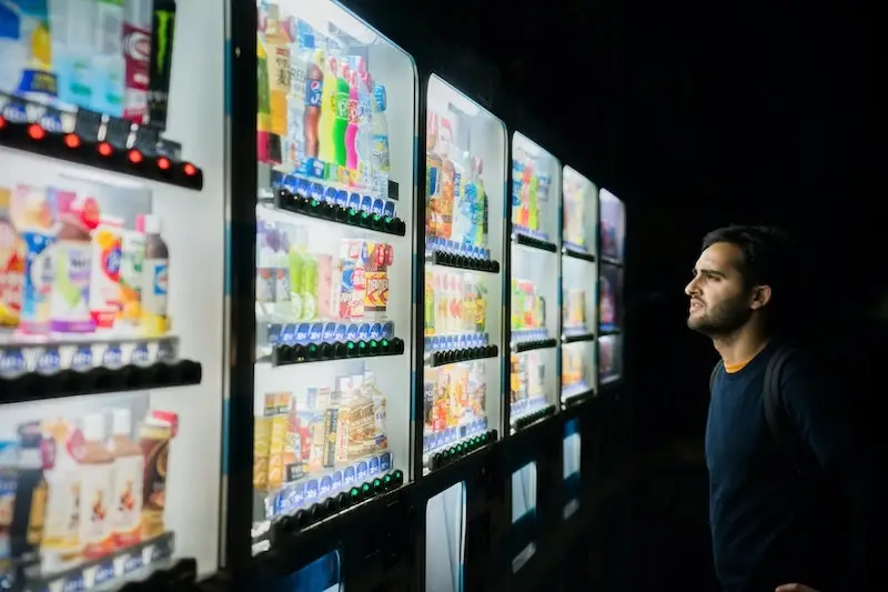 Man Looking At Vending Machines man looking at drinks in vending machine