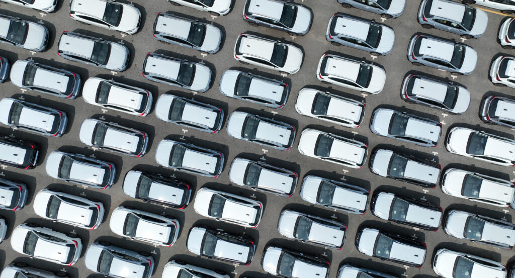 Baader Meinhof Phenomenon 4 aerial view of a parking lot full of identical white cars, illustrating the baader-meinhof phenomenon, where you buy a car and start seeing it everywhere.
